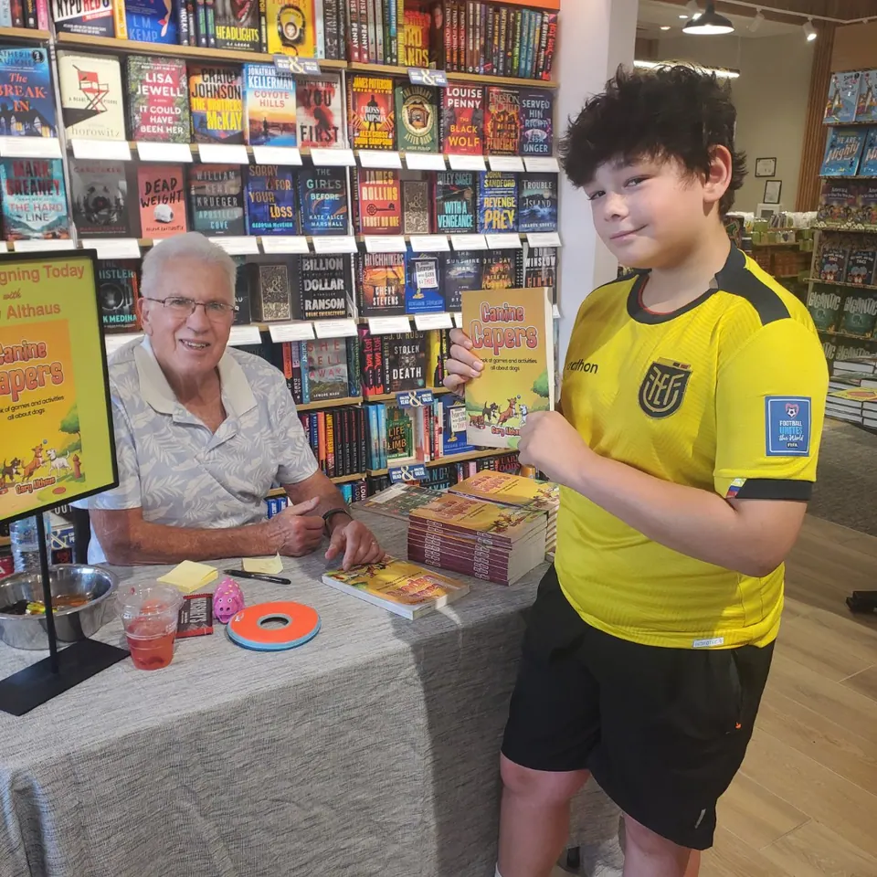 Gary Althaus at his book-signing table at Barnes & Noble in Beavercreek, Ohio, with a young reader holding a copy of Canine Capers.